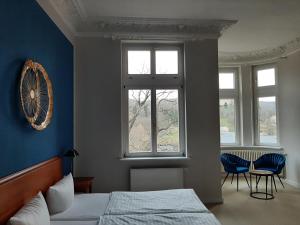 a bedroom with a bed and two chairs and windows at Hotel Villa Viktoria Luise in Blankenburg