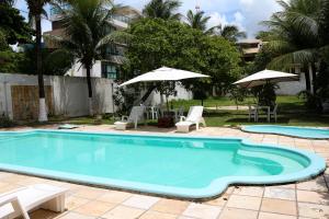 a large swimming pool with chairs and umbrellas at Pousada Parador 081 in Porto De Galinhas