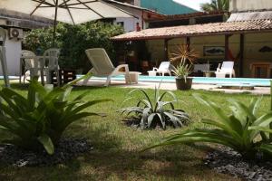 a yard with a pool and chairs and a house at Pousada Parador 081 in Porto De Galinhas