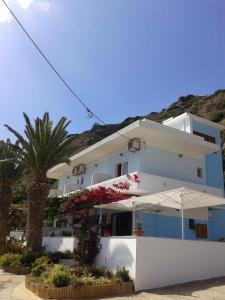 a white building with a palm tree in front of it at Skinos Apartments in Plakias