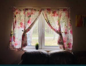 ein Fenster mit einem geblümten Vorhang im Wohnzimmer in der Unterkunft Domek Chańcza in Chańcza