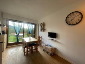 a dining room with a table and a clock on the wall at T2 avec jardin privatif - Le Diamant in Villard-de-Lans