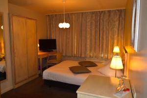 a bedroom with a bed and a desk and a television at Oranje City Hotel in Diest