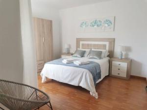 a bedroom with a bed and a chair in it at Apto Playa Camelle 1º in Camelle