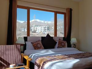a bedroom with two beds and a large window at Hotel Malik Residency in Leh