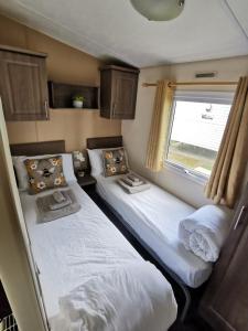 Newquay Caravan Holiday في نيوكواي: سريرين في غرفة صغيرة مع نافذة