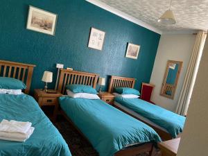 two beds in a room with blue walls at Dinorben Arms Hotel in Amlwch