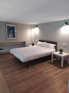 a bedroom with a large white bed and a table at Apartamento Retiro in Madrid