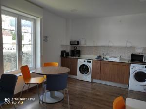 a kitchen with a table and a washing machine at Albergue de Santullán in Castro-Urdiales