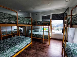 a room with three bunk beds and a window at Albergue de Santullán in Castro-Urdiales