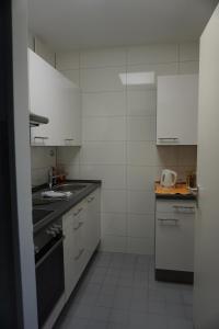 a small kitchen with white cabinets and a sink at Bett3de in Erding