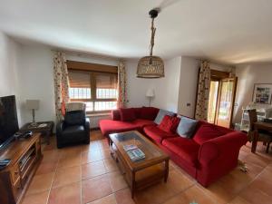 Casa rural Las Vegas في Pelayos de la Presa: غرفة معيشة مع أريكة حمراء وطاولة