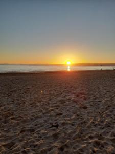 een persoon die bij zonsondergang op het strand loopt bij The Dolphin Hotel Exmouth in Exmouth