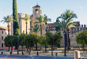 a view of a building with palm trees and a clock tower at San Basilio´s Red House in Córdoba