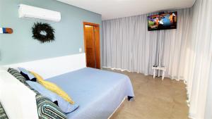1 dormitorio con 1 cama y TV en la pared en 1082 - Flat Vista para o Mar e Piscina privativa em Bombinhas, en Bombinhas