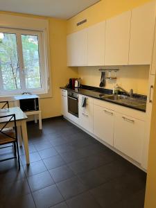 eine Küche mit weißen Schränken, einem Tisch und einem Fenster in der Unterkunft Alpes Rez in Neuenburg