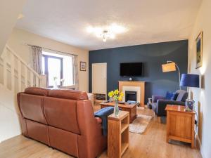 een woonkamer met een bank en een tv bij Sealladh an Locha Cottage in Kensaleyre