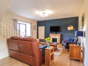 a living room with a couch and a tv at Sealladh an Locha Cottage in Kensaleyre