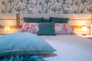 1 dormitorio con cama con almohadas azules y papel pintado en Ke Casetta Tenerife, en Costa del Silencio