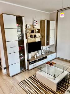 a living room with a glass coffee table and a television at SWEET APP AM SEE in Pönitz am See