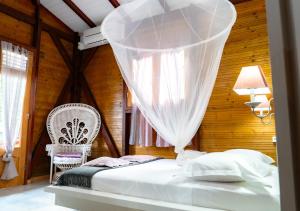 een slaapkamer met een wit bed en een stoel bij La Savannah Villa in Labuthie