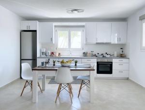 a kitchen with white cabinets and a table and chairs at Nostos home in Dhragoulás