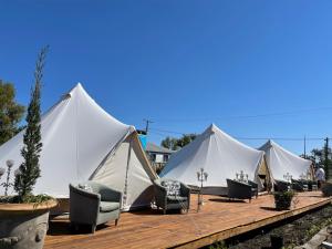 rząd białych namiotów siedzących na drewnianym pokładzie w obiekcie Club Boutique Hotel Cunnamulla w Cunnamulli