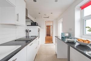 a kitchen with white cabinets and a counter top at Wave Cottage by Bloom Stays in Sandgate +25 photos