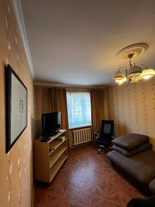 uma sala de estar com uma televisão, um sofá e uma cadeira em Nice and Cosy two bedrooms parking balcony apartment em Riga