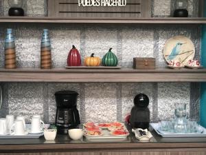 a shelf with plates of food and a coffee maker at Hotel Ayenda House Concepción 1317 in Barranquilla