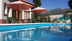 a swimming pool with umbrellas and tables and chairs at DEL INFINITO in Capilla del Monte