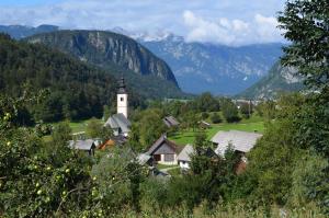 a village with a church and mountains in the background at Apartment Brumec in Bohinj