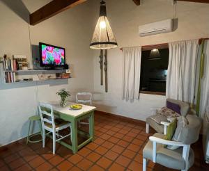 een woonkamer met een tafel en stoelen en een televisie bij GOLF - Casa de huéspedes in Tandil