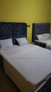 two beds in a room with a yellow wall at Jennabwa Lodge and Restaurant in Freetown