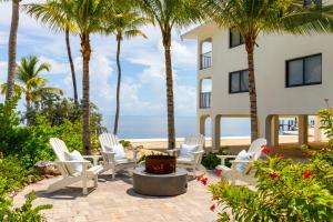 eine Terrasse mit weißen Stühlen, Palmen und dem Meer in der Unterkunft La Siesta Resort & Villas in Islamorada