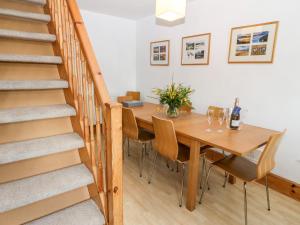 a dining room with a table and a staircase at Awel Y Mor in Pwllheli