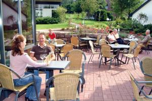 un groupe de personnes assises à des tables dans un patio dans l'établissement Ringhotel Posthotel Usseln, à Willingen