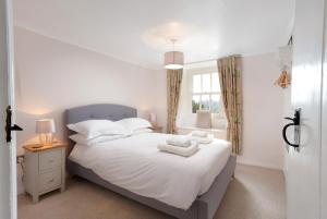 a bedroom with a bed with white sheets and a window at Rhubarb Cottage in Chapel Stile
