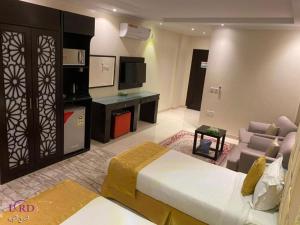 Abū Qa‘arにあるAl Lord Hotelのベッド、ソファ、テレビが備わるホテルルームです。