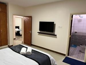 a bedroom with a bed and a tv on the wall at Champions Chill Suite in Eldoret