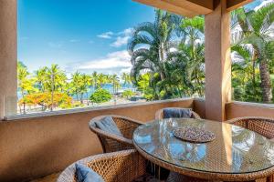 a balcony with a table and chairs and palm trees at Kahalu'u Beach Villas 1-203 in Kailua-Kona