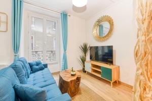 a living room with a blue couch and a tv at Bien-être et bonheur au pied des Thermes in Allevard