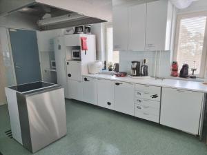 a kitchen with white cabinets and a refrigerator at Hotel Vanha-Merivartioasema in Kotka