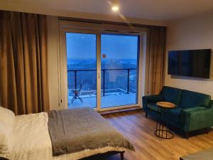 ein Schlafzimmer mit einem Bett und einer Couch und einem großen Fenster in der Unterkunft APARTAMENT W CHMURACH- 15 PIĘTRO OSIEDLE TYSIĄCLECIA- parking w hali garażowej, wielki taras z widokiem na zachód słońca in Kattowitz