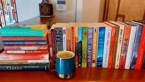 une pile de livres sur une table avec une tasse de café dans l'établissement Hotel Mercante, à Vigan