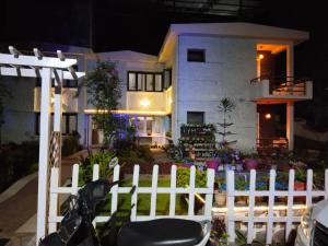 uma cerca branca em frente a uma casa à noite em Hotel Seven Roads em Kodaikanal
