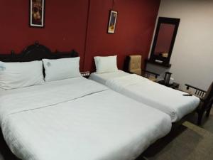 two white beds in a room with red walls at Hotel Seven Roads in Kodaikānāl