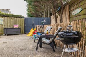 a patio with a grill and chairs and a playground at BeachHouse Oase aan Zee in Noordwijk