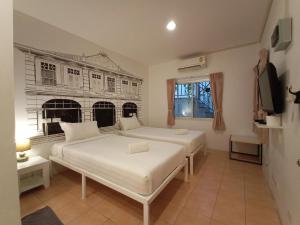 a white bedroom with two beds and a tv at Chino Town Gallery Alley - SHA Plus in Phuket