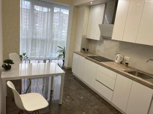 cocina con armarios blancos, fregadero y mesa en 2 кімнатні ,Люкс апартаменти в ЖК Арена ,район автовокзалу, en Rivne